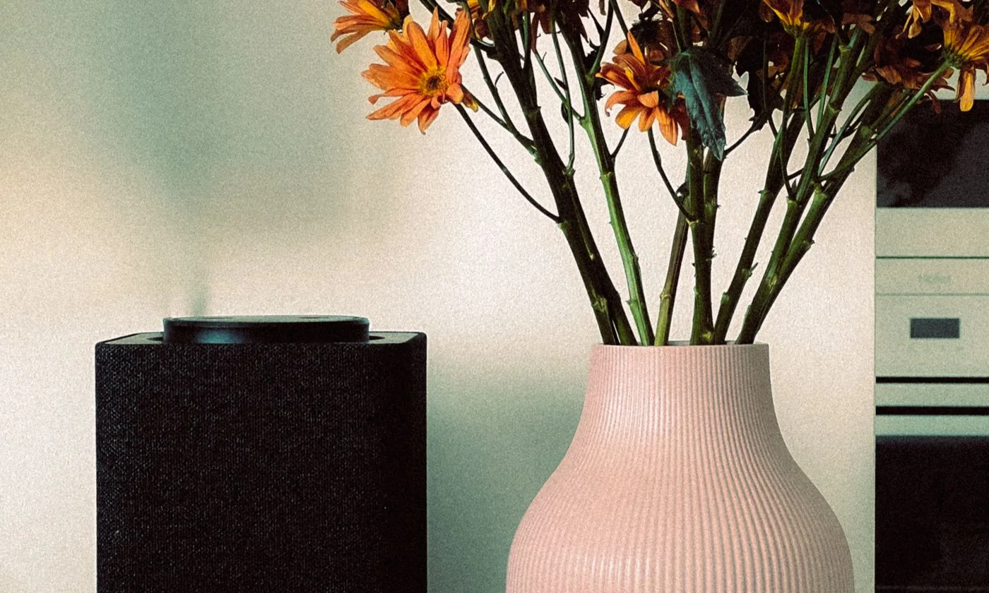 Air purifier beside a vase of flowers and mugs in a home