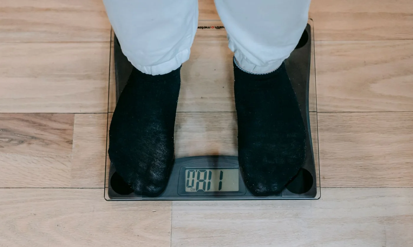 Person in socks standing on a digital bathroom scale on a wooden floor